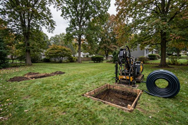 Trenchless pipe bursting setup with two small access pits in an undisturbed Red Lion lawn